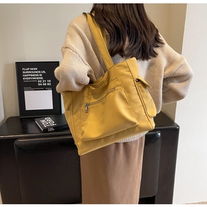 Detail view of bright yellow canvas tote bag with functional pockets and side flap pouch
