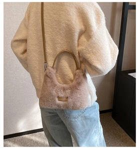 Détail du sac à main en peluche douce avec poignée ronde et plaque dorée gravée