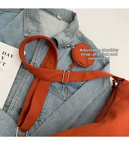 Détail du sac bandoulière en toile orange avec sangle réglable et petite pochette ronde