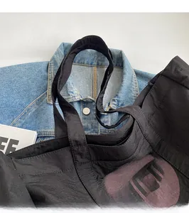 Détail du cabas en nylon noir avec imprimé COCO et large bandoulière confortable