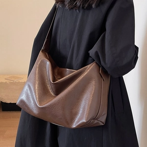 Large dark brown leather tote bag with a soft minimalist design and wide shoulder strap