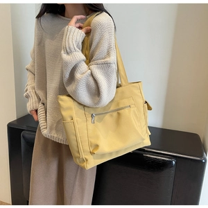 Detail of yellow canvas tote bag with front zipper pocket and side pouch for storage