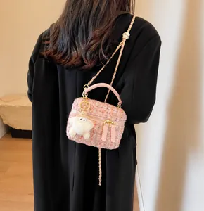 Pink tweed chain bag detail featuring a whimsical white pom-pom charm with big eyes