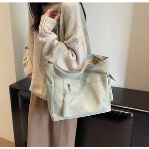 Detail of mint green canvas tote bag featuring front zipper pocket and side slip pockets