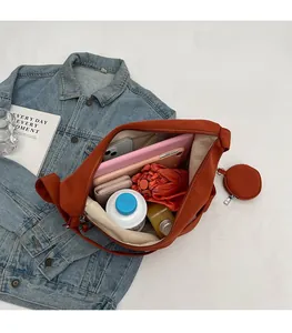 Intérieur spacieux du sac bandoulière orange montrant le rangement pour tablette et objets
