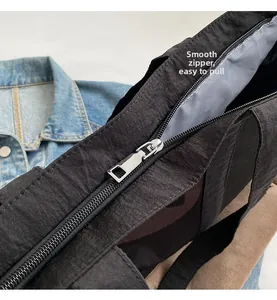 Détail d'un sac cabas noir en toile avec fermeture éclair en métal argenté et doublure grise