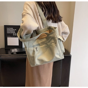 Detail of light green canvas tote bag showing multiple pockets and durable texture