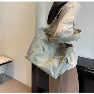 Detail view of large mint green canvas tote bag featuring side pockets and wide shoulder strap