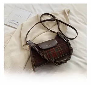 Detail of vintage brown leather and plaid crossbody bag with dual shoulder straps