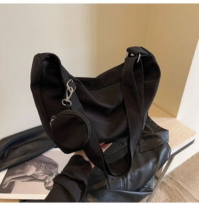 Détail du sac croissant en toile noire avec une mini pochette ronde amovible et fermeture