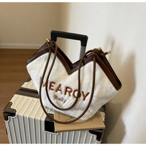 Nahaufnahme der weißen Plüschtasche mit braunem Lederbesatz und Stickerei-Details