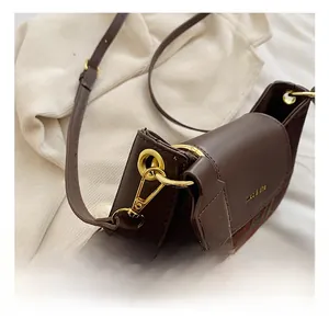Close-up of brown leather stitching and green plaid fabric on this small crossbody bag