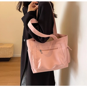 Detailed view of a pink large capacity canvas tote bag worn by a model in a warm interior