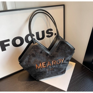 Detailaufnahme der schwarzen Kunstfelltasche mit V-förmigem Lederbesatz und Stickerei
