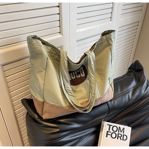 Détail du sac cabas en toile verte avec base en daim marron et logo UCO distinctif