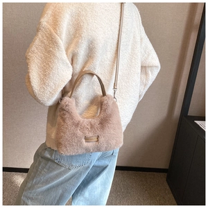 Detail of light brown plush crossbody bag with leather strap and metal engraved plate