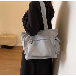 Detail of light blue canvas tote bag with side pockets and front zipper for daily commute