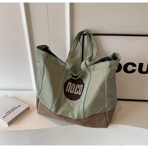Détail du cabas en toile vert sauge montrant le logo noco et la couture en daim
