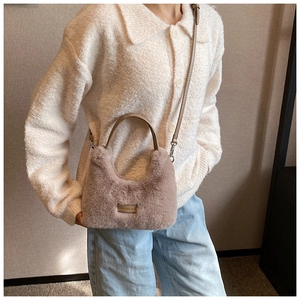 Détail du sac à bandoulière en peluche lavande avec texture en fourrure et plaque logo