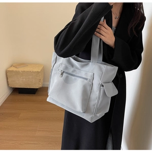 Detail of grey canvas tote bag with front zipper pocket and side flap pocket for commute