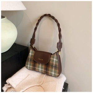 Detail of the braided leather handle and green plaid fabric on the vintage shoulder bag