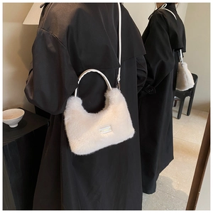 Détail d'un sac hobo en peluche blanche avec étiquette sur fond de manteau noir chic