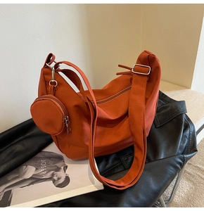 Gros plan d'un sac dumpling orange avec petit porte-monnaie rond sur une veste en cuir
