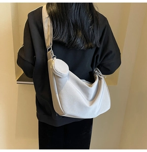 Sac bandoulière demi-lune gris avec petit porte-monnaie et large bandoulière porté par mannequin