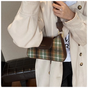 Detailed close-up of plaid fabric texture and leather flap on retro shoulder bag