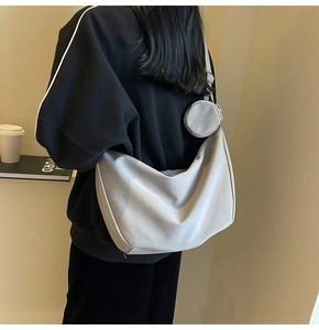 Sac bandoulière en toile grise avec mini porte-monnaie porté par un mannequin en extérieur
