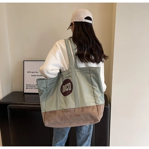 Détail montrant les coutures contrastées en nylon vert et daim marron du sac cabas