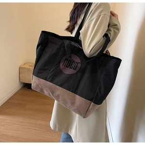 Gros plan d'un grand sac cabas en toile noire avec une base en daim marron élégante