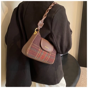Close-up of retro plaid shoulder bag featuring woven leather strap and gold hardware