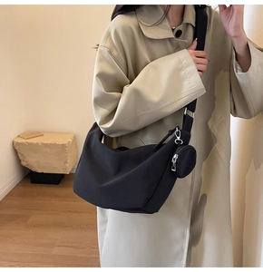 Détail d'un sac bandoulière en nylon noir avec sangle réglable et petit porte-monnaie