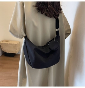 Détail d'un sac bandoulière demi-lune noir avec une petite pochette ronde assortie sur la sangle