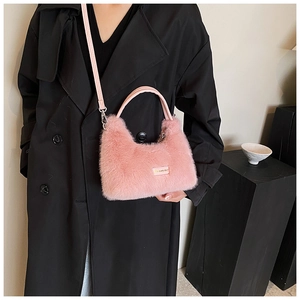 Détail d'un sac à main rose en fausse fourrure avec poignée en cuir et bandoulière métal