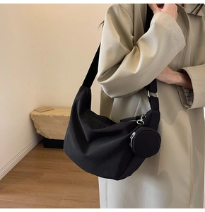 Modèle portant un sac hobo noir en demi-lune avec un petit porte-monnaie assorti