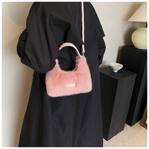 Detail of pink faux fur crossbody bag with soft texture on a black coat outfit
