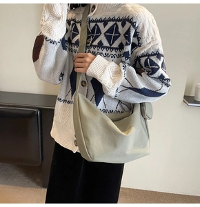 Détail du sac demi-lune en toile vert sauge porté avec un cardigan en maille rétro