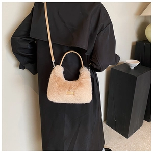 Détail du sac à main en fausse fourrure beige avec bandoulière en cuir et logo métallique