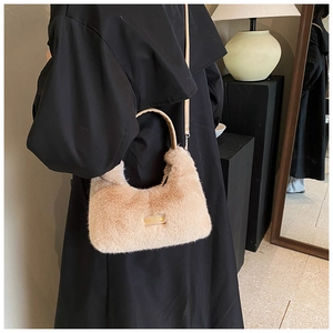 Détail du sac demi-lune en fausse fourrure marron clair avec poignée en cuir sur manteau