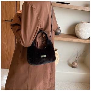 Sac à main en peluche noire avec étiquette jaune porté dans un décor intérieur douillet