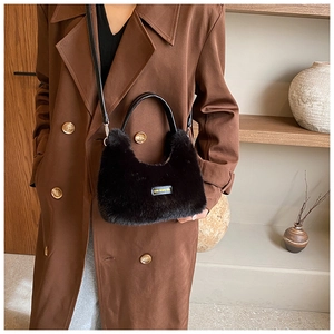 Détail du sac à main en peluche noire avec étiquette love every day et poignée en cuir