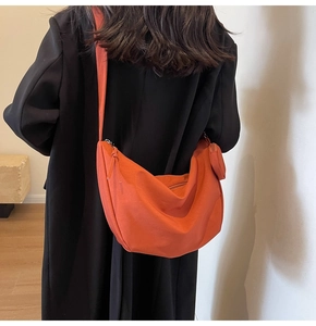Détail du sac croissant en toile orange avec un petit porte-monnaie rond assorti