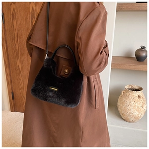 Detail of plush black fur handbag with love every day tag on brown winter coat