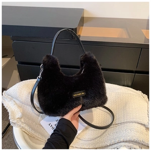 Détail d'un sac à main noir en fausse fourrure avec écusson en cuir et boucles argentées