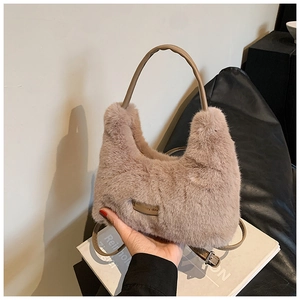 Close-up of dusty pink plush handbag featuring soft faux fur and gold brand plaque detail