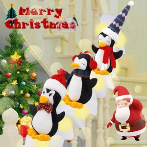 Three festive plush penguins with Christmas hats and scarves set by a lit holiday tree