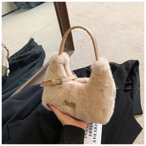 Detail of beige faux fur handbag showing smooth brown leather handle and metal buckle