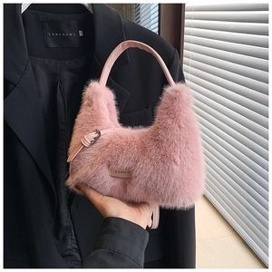 Detailed close-up of pink faux fur handbag featuring leather handles and gold metal buckles